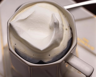 white ceramic mug with coffee and whip cream